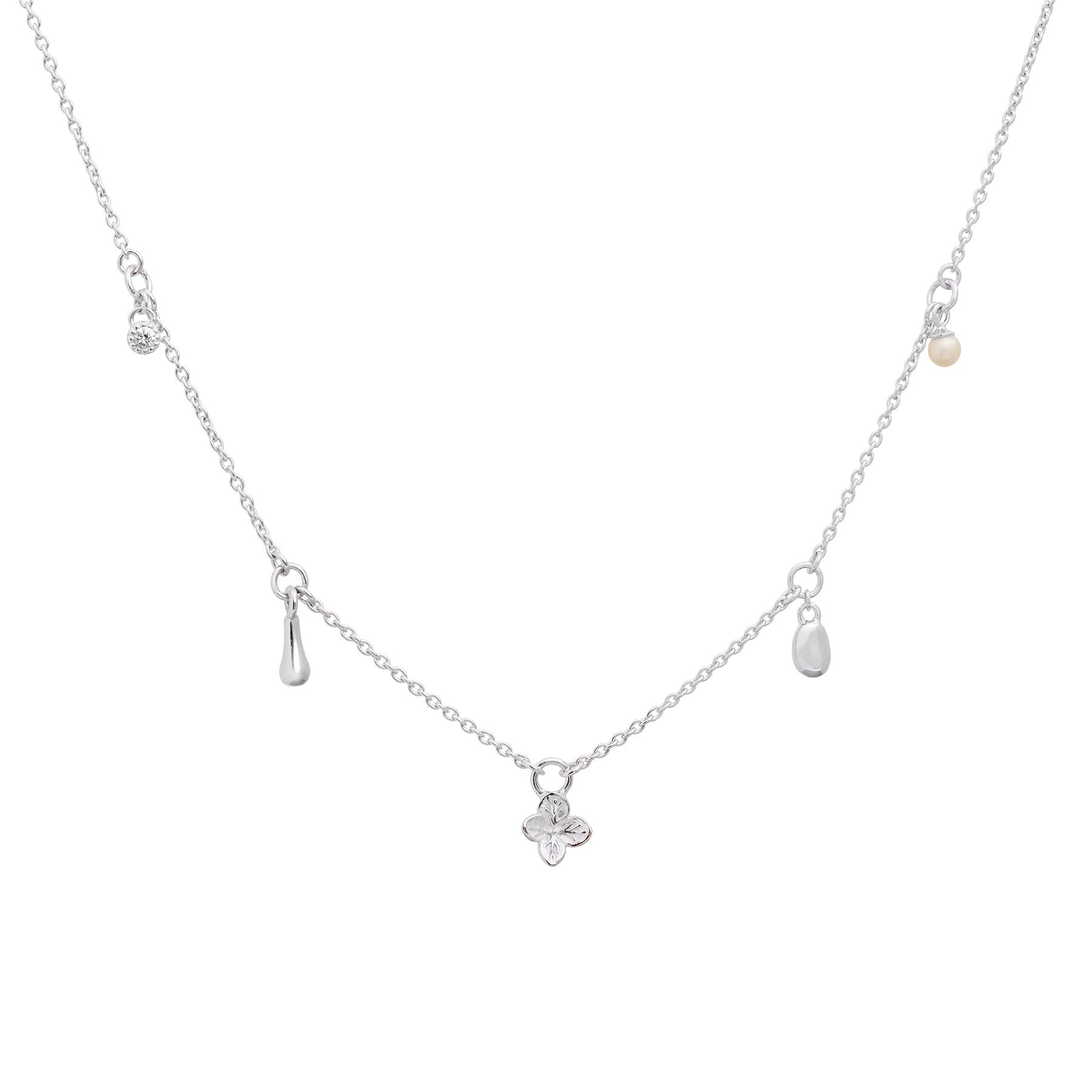Close up image of a sterling silver charm necklace featuring a flower, pearl and organic-shaped charms