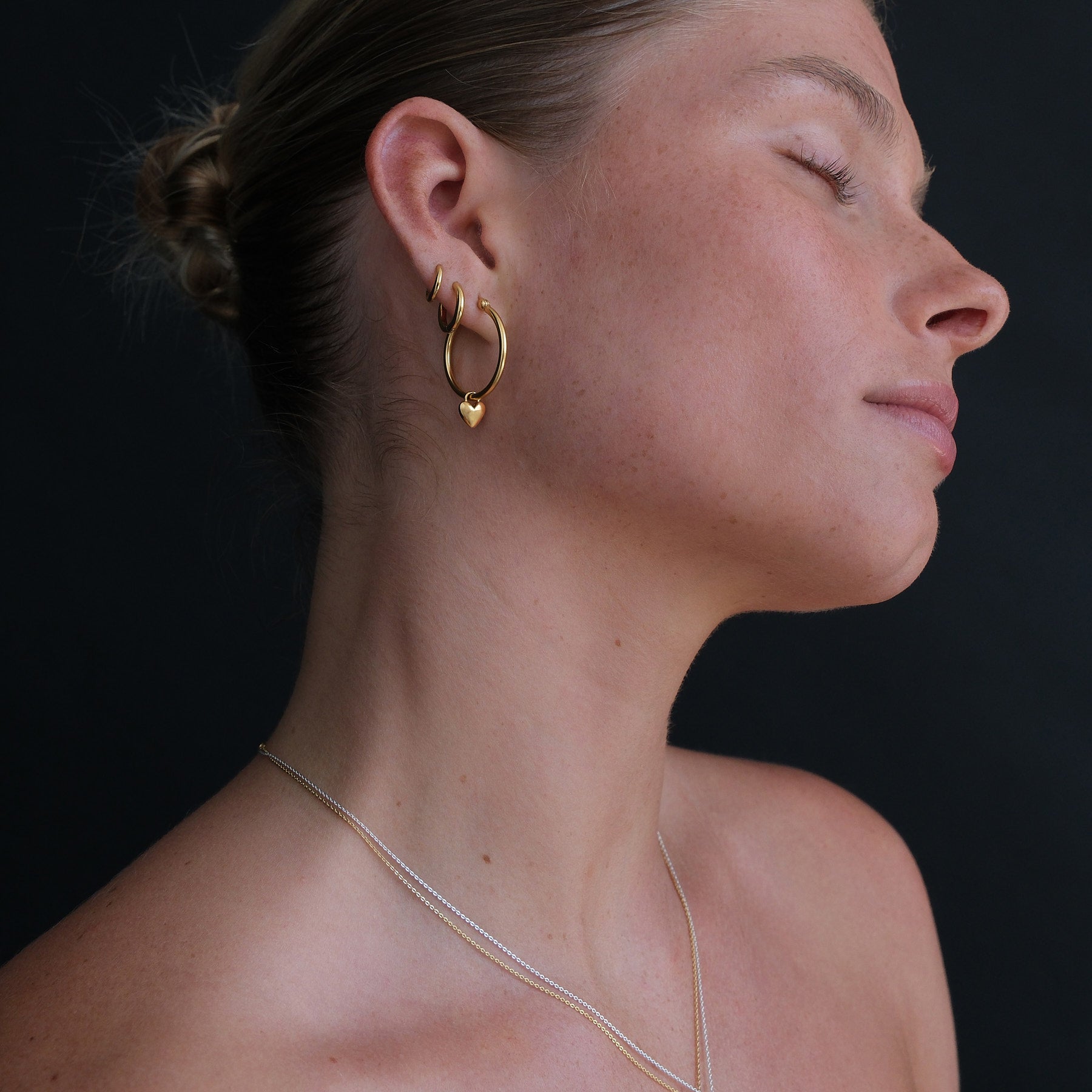 Side profile of model wearing 19k gold vermeil huggies and hoop earrings.