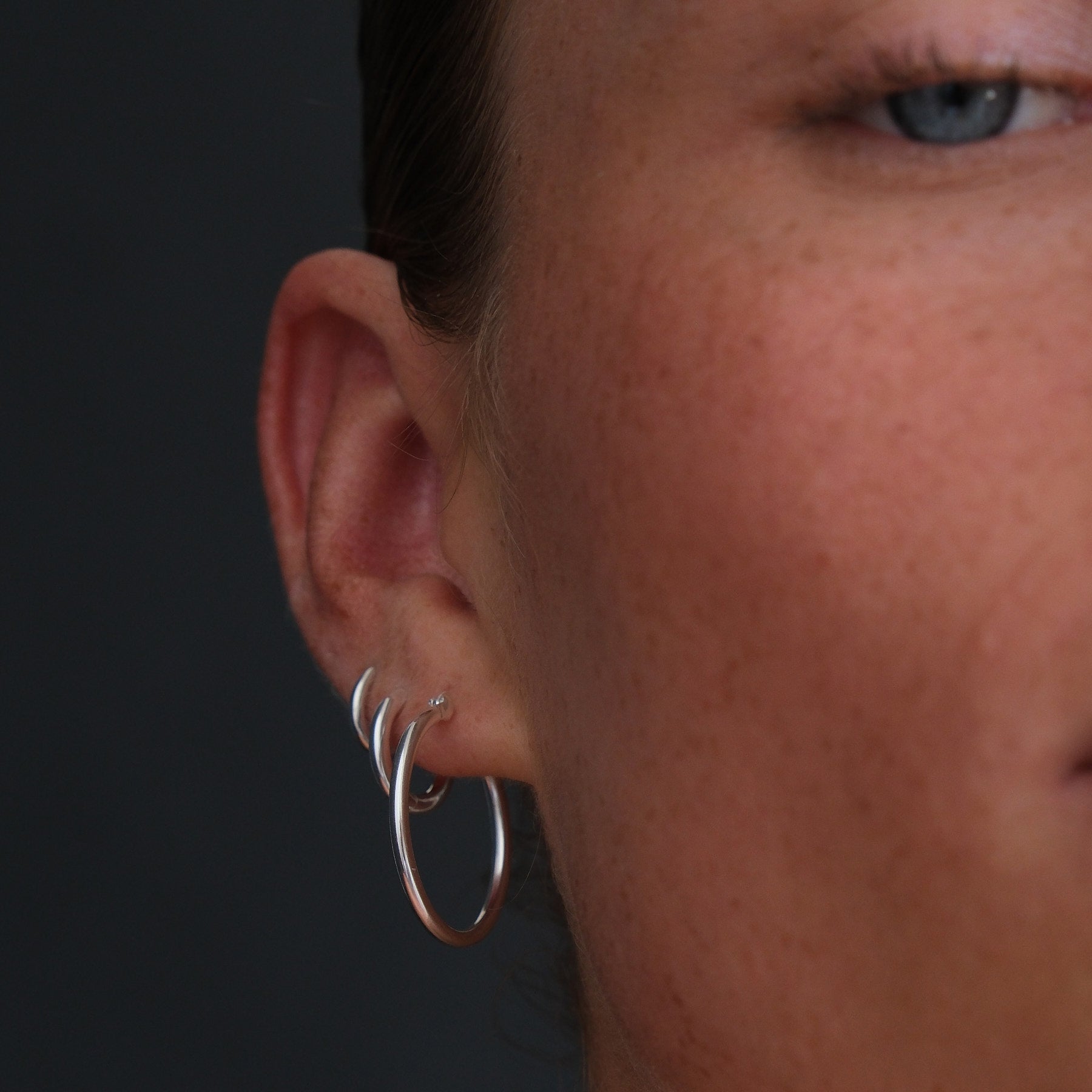 Front view of model wearing sterling silver hoop and huggie earrings.