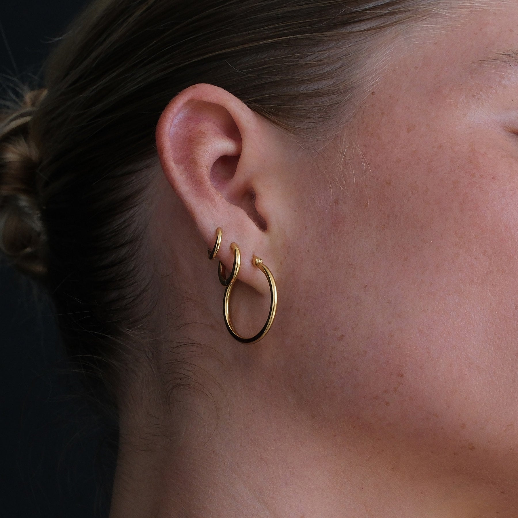 Close up detail of layered gold hoop earrings.