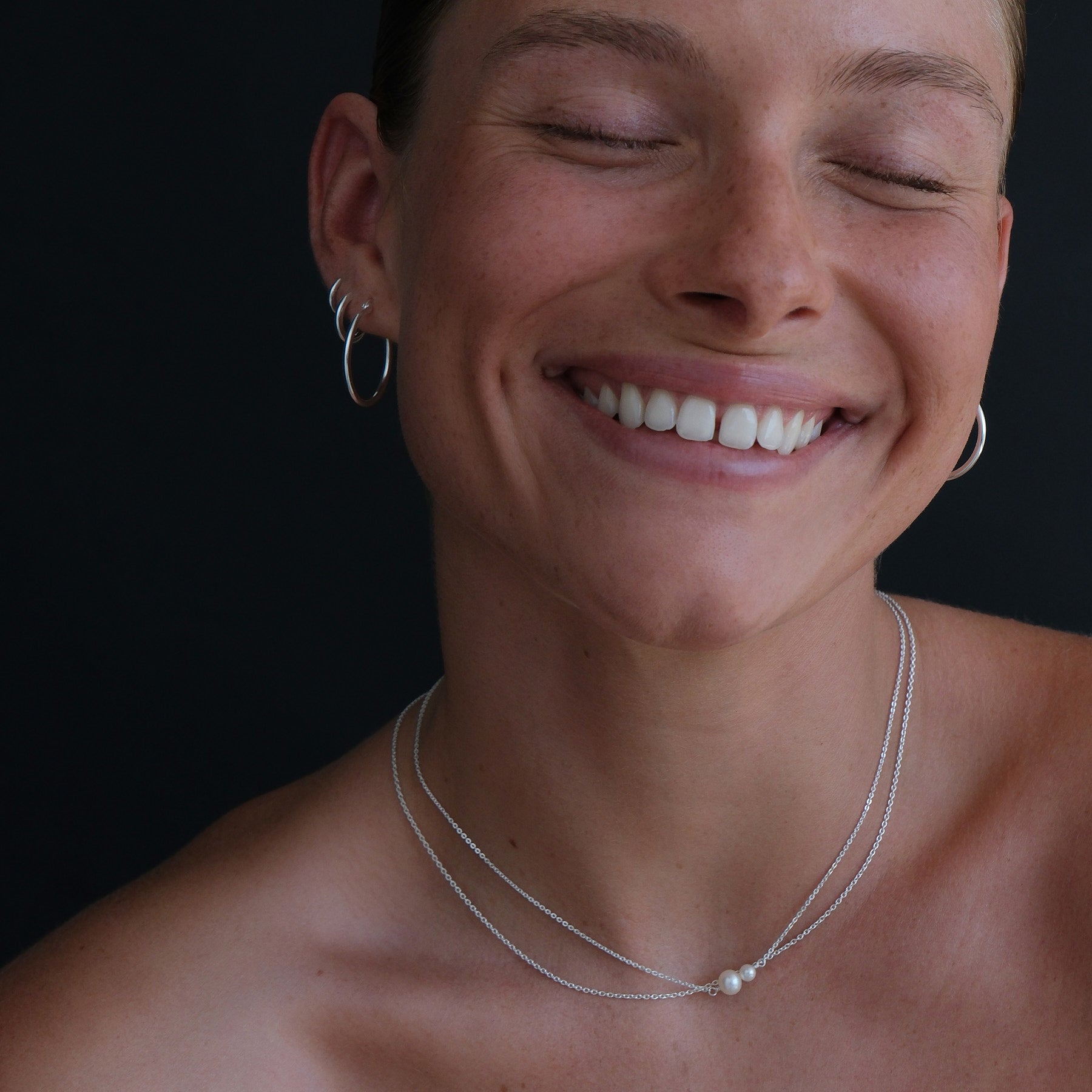 Close up of model wearing double pearl necklace in sterling silver along with a fine sterling silver chain.