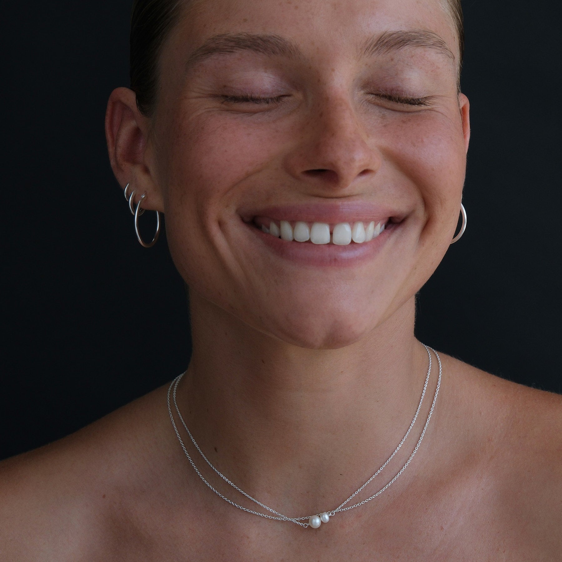Model is wearing a double pearl sterling silver necklace layered with a fine sterling silver chain. 