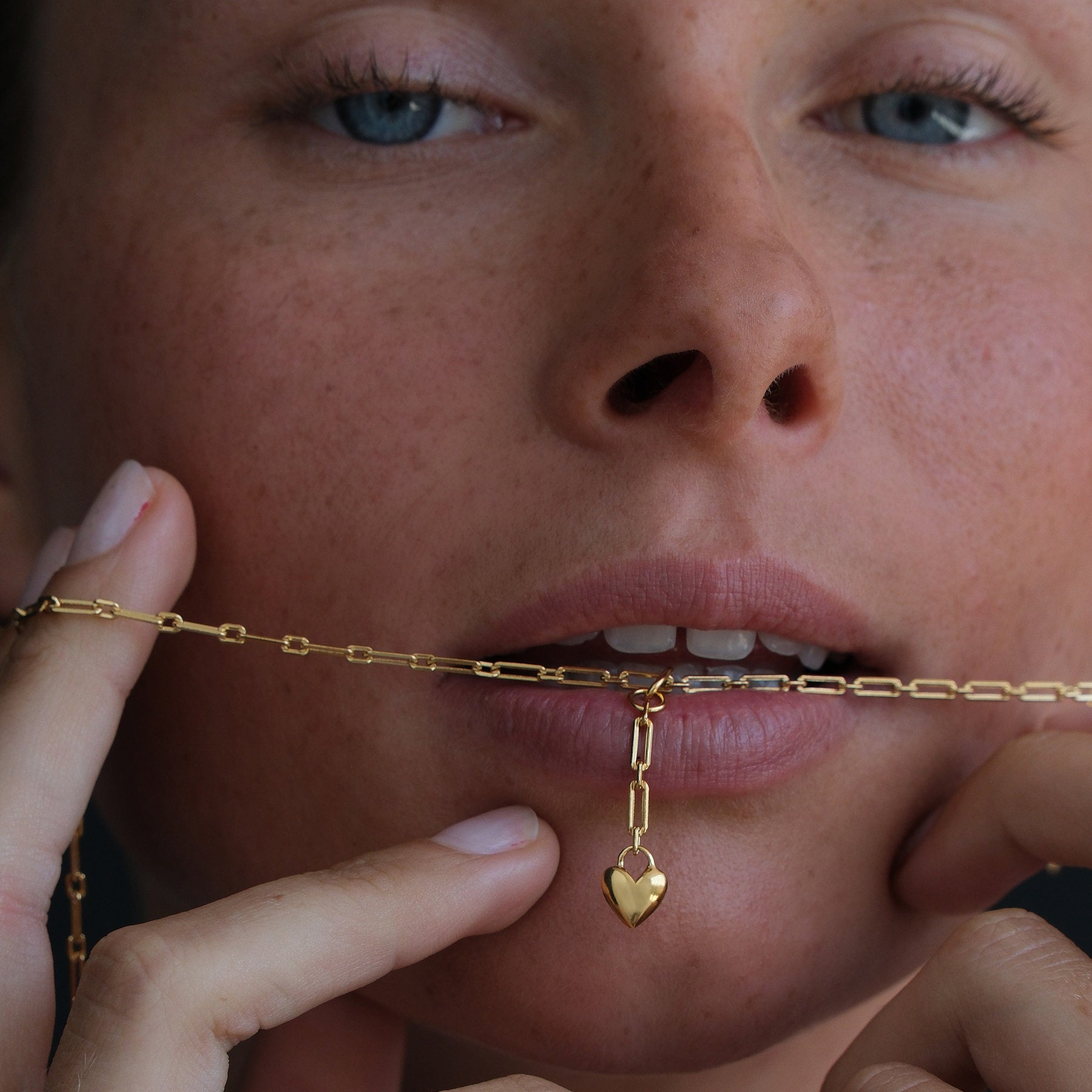Model wearing an 18k gold vermeil chain necklace with a heart charm drop pendant
